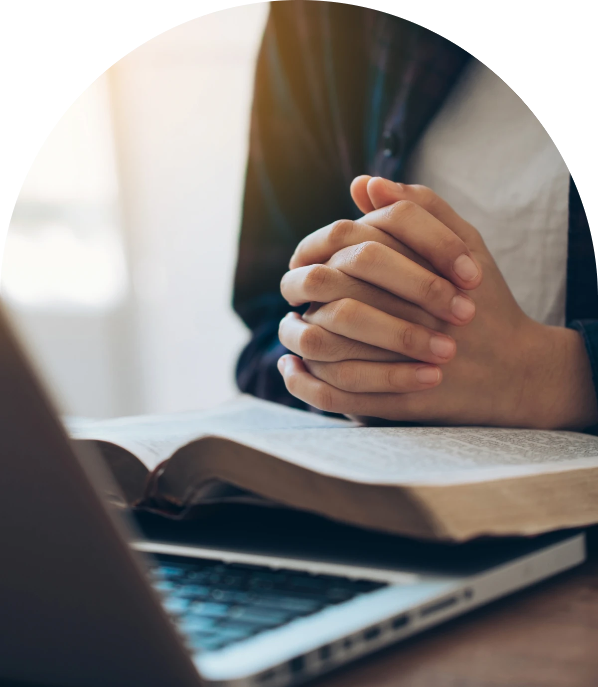 Hands clasped in prayer over book